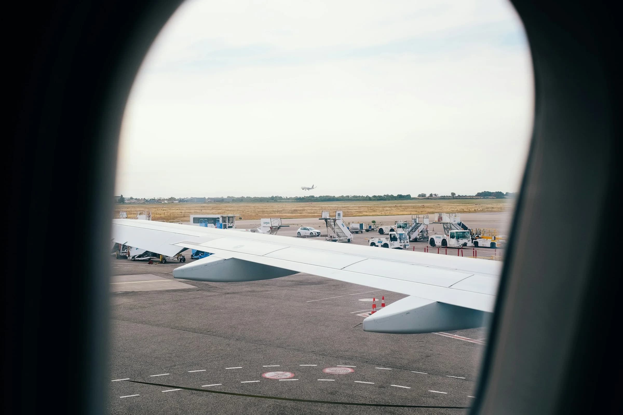 Asa de avião vista pela janela, no pátio do aeroporto