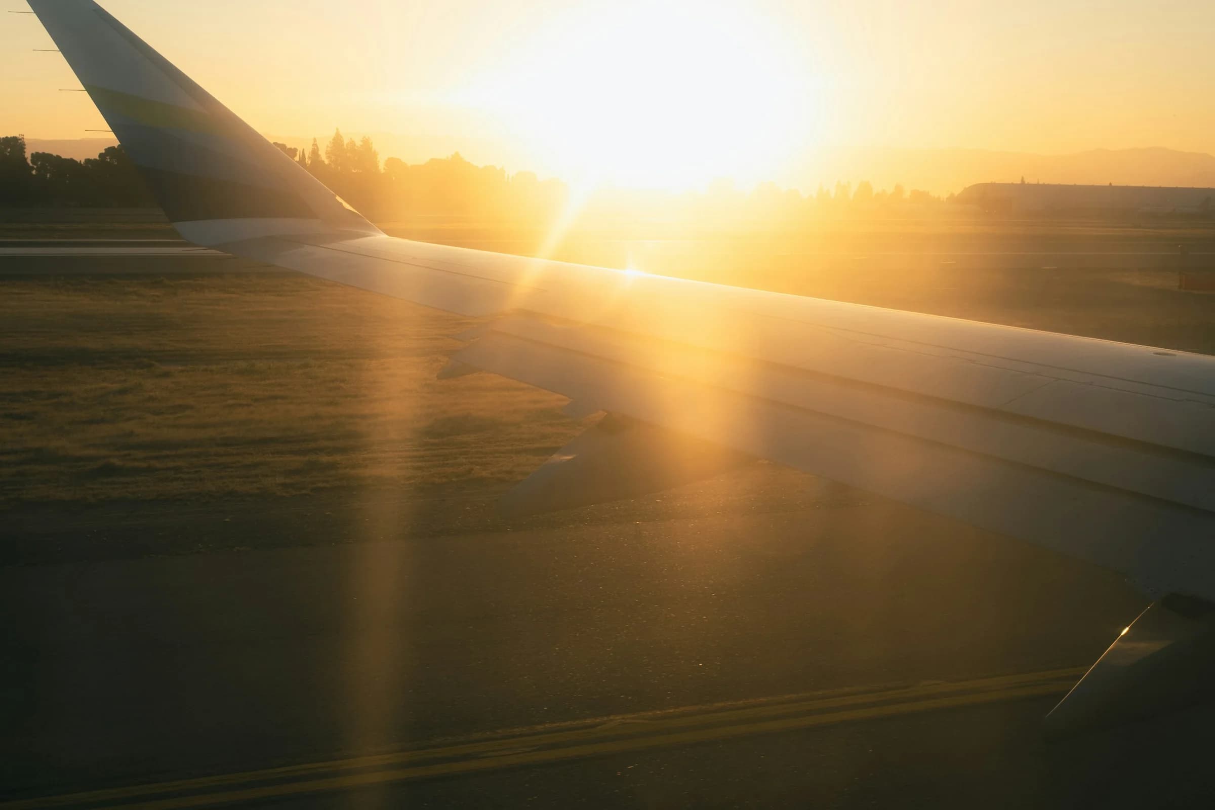 Asa de avião ao nascer do sol sobre a pista